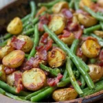 Country Ranch Green Beans ‘n Potatoes with Bacon Introduction Country Ranch Green Beans ‘n Potatoes with Bacon is a delicious and hearty side dish that combines fresh green beans, tender baby potatoes, and crispy bacon, all flavored with ranch seasoning. This recipe is perfect for family dinners and gatherings. It’s simple to make and packed with flavors everyone will love. Why Make This Recipe Making Country Ranch Green Beans ‘n Potatoes with Bacon is a fantastic choice for several reasons. First, it uses fresh and wholesome ingredients that are easy to find. Second, the combination of flavors from the bacon and ranch seasoning makes this dish incredibly tasty. Lastly, it’s a great way to include vegetables in your meal while still enjoying a comforting and satisfying side. How to Make Country Ranch Green Beans ‘n Potatoes with Bacon Ingredients: 1 pound green beans, trimmed and cut into bite-sized pieces 1 pound baby potatoes, halved or quartered 6 strips bacon, diced 1 packet ranch seasoning mix (1 ounce) 1/2 cup chicken broth 2 tablespoons olive oil 1/2 teaspoon garlic powder 1/2 teaspoon onion powder Salt and pepper, to taste Directions: In a large skillet or Dutch oven, cook the diced bacon over medium heat until crispy. Remove bacon with a slotted spoon and set aside, leaving the bacon fat in the pan. Add olive oil to the bacon fat in the same pan. Add the potatoes and cook for about 5-7 minutes, until they start to brown. Add the green beans to the pan with the potatoes and cook for another 3-4 minutes, stirring occasionally. Sprinkle the ranch seasoning mix, garlic powder, and onion powder over the vegetables and stir to coat evenly. Pour in the chicken broth, bring to a simmer, cover, and cook for 15-20 minutes, until the potatoes are tender and the green beans are cooked. Stir in the cooked bacon and season with salt and pepper to taste. Serve warm as a delicious side dish. How to Serve Country Ranch Green Beans ‘n Potatoes with Bacon This dish is best served warm. It pairs well with many main courses, such as roasted chicken, grilled meats, or barbecue dishes. You can place it in a serving bowl and sprinkle some extra bacon bits on top for a nice presentation. How to Store Country Ranch Green Beans ‘n Potatoes with Bacon To store leftovers, let them cool completely and then place them in an airtight container. You can keep them in the refrigerator for up to 3 days. To reheat, simply microwave them until warmed through, or heat them in a skillet over medium heat. Tips to Make Country Ranch Green Beans ‘n Potatoes with Bacon For an extra flavor boost, add a pinch of crushed red pepper flakes to the dish. If you like a crispier texture, finish the dish under the broiler for a few minutes before serving. Feel free to adjust the seasoning according to your taste. Variation You can easily make this dish vegetarian by skipping the bacon and using vegetable broth instead of chicken broth. You may also add other vegetables like bell peppers or carrots for more color and nutrition. FAQs 1. Can I use frozen green beans for this recipe? Yes, you can use frozen green beans. Just be sure to thaw them before cooking. 2. How long does it take to prepare this dish? The total time to prepare and cook this dish is about 35-40 minutes. 3. Is this dish gluten-free? Yes, this recipe is gluten-free, as long as you use a gluten-free ranch seasoning mix.