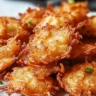 Crispy Amish Onion Fritters served on a plate, garnished with herbs
