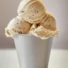 A scoop of Dr. Pepper ice cream topped with chocolate syrup and cherries