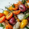 Garlic herb roasted veggies in a serving dish garnished with fresh herbs.