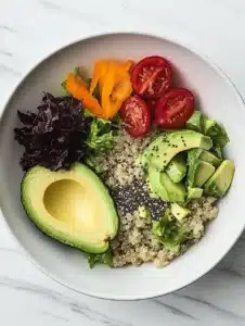 Quinoa salad with avocado and chia seeds in a bowl, garnished with fresh herbs.