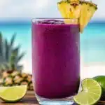 Hibiscus tea pineapple smoothie served in a glass with fresh fruit garnish
