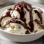 A bowl of creamy homemade vanilla ice cream topped with chocolate sauce