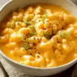 Bowl of creamy Mac and Cheese Soup topped with cheese and herbs