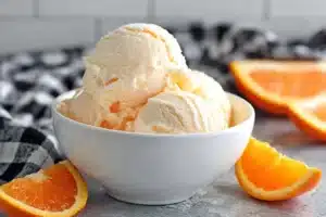 Delicious bowl of orange ice cream topped with orange slices
