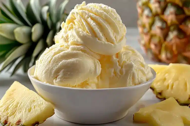 Bowl of homemade pineapple ice cream topped with fresh pineapple slices
