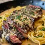 Plate of creamy Cajun Steak Alfredo garnished with herbs