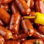 Slow cooker Mississippi Lil Smokies garnished with pepperoncini and served as an appetizer.