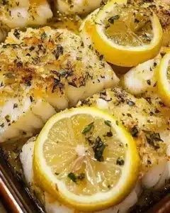 Plate of baked cod with lemon and garlic garnished with herbs