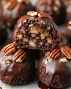 Gooey Pecan Pie Brownie Bombs 3 Gooey pecan pie brownies topped with pecan pieces on a wooden table