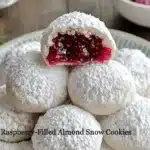 Raspberry-filled almond snow cookies on a festive plate
