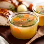 Homemade turkey stock simmering in a pot with herbs and vegetables.