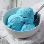 A scoop of Blue Moon Ice Cream in a waffle cone topped with sprinkles