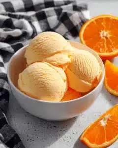 Delicious homemade orange ice cream served in a bowl with orange slices