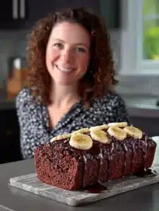 Slice of triple chocolate banana bread with chocolate chunks on a wooden plate.