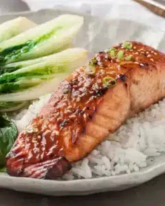Asian Glazed Salmon drizzled with sticky maple-soy glaze on a white plate