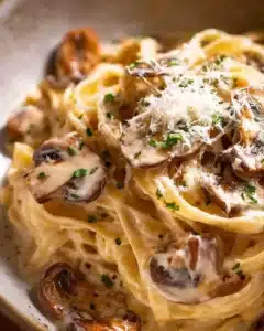 Bowl of creamy mushroom pasta topped with fresh herbs and grated cheese