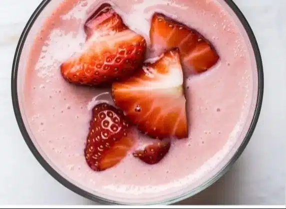 High-protein strawberry peach smoothie in a glass with fresh fruit