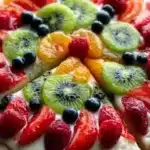 A colorful, delicious fruit pizza topped with fresh fruits and creamy frosting.