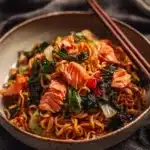 Teriyaki salmon served over a bed of noodles with vibrant vegetables.