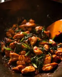 Plate of Thai Chilli Basil Chicken garnished with fresh basil leaves