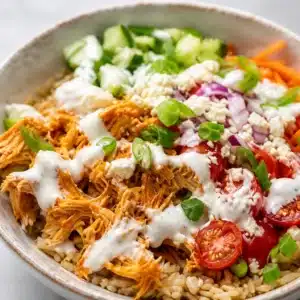 Healthy buffalo chicken bowl with shredded chicken, fresh veggies, and ranch dressing.