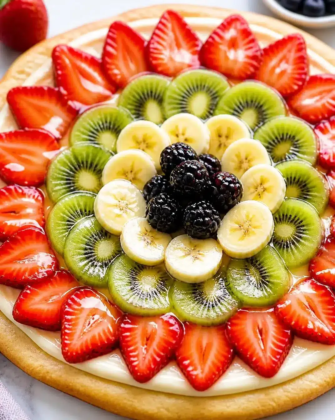 Colorful fruit pizza topped with a sweet glaze and fresh fruits on a crust