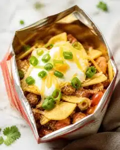 A colorful bowl of walking tacos topped with fresh ingredients and served in a bag