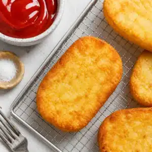 Crispy air fryer hash browns served with a side of dipping sauce.