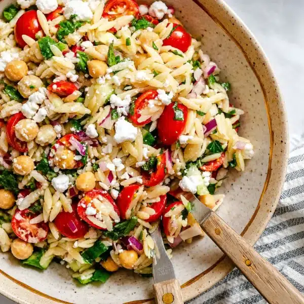 Colorful orzo pasta salad with fresh vegetables and creamy feta cheese.