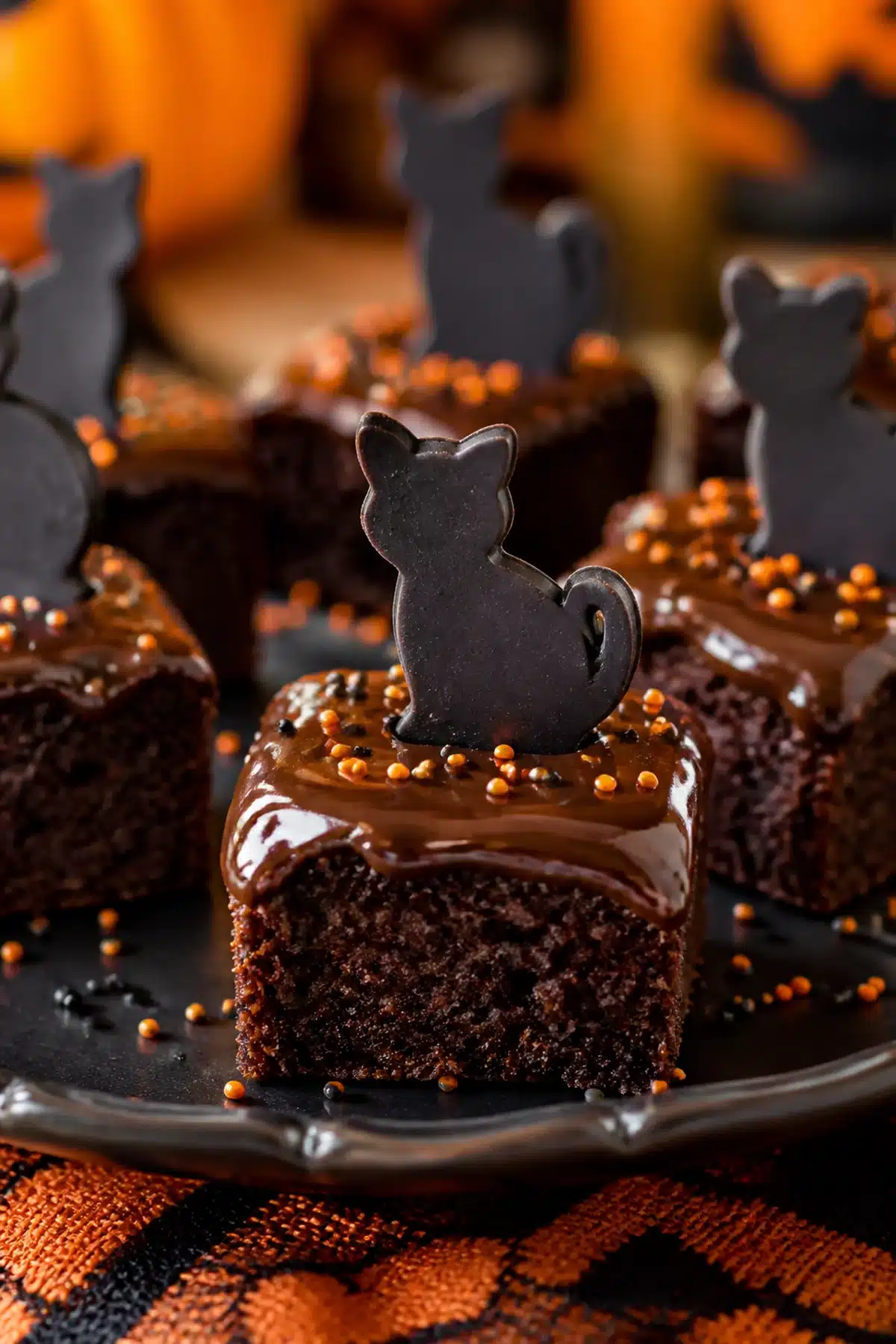 Black cat brownie bites with glossy ganache, orange sprinkles and chocolate cat toppers