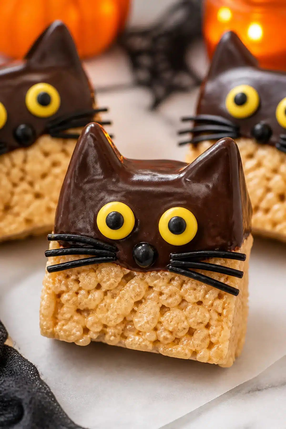 Black cat rice cereal treats dipped in chocolate with candy eyes and whiskers